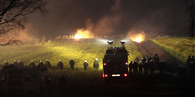 Burning barricades confront water cannon at night, in Castor protests