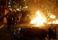 Greek cops run past burning barricades